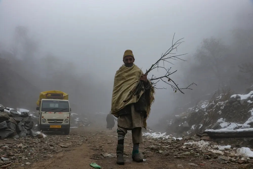 24 October 2021, India, Srinagar: A man from the nomadic Bakarwal tribe carries firewood on a foggy morning in the outskirts of Srinagar. Photo: Adil Abbas/ZUMA Press Wire/dpa.