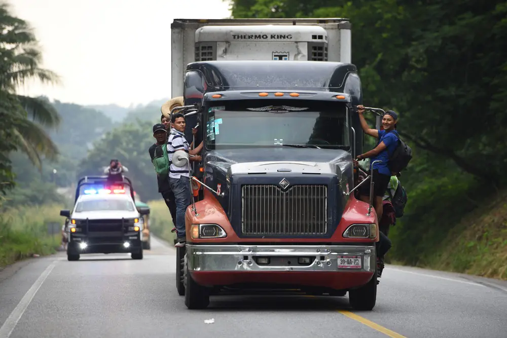18 November 2021, Mexico, Heroic Veracruz: Migrants from Central America stand at the sides of a truck driving them forward a short distance on their march toward the US border. Photo: Yahir Ceballos/dpa.