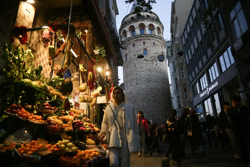 21 November 2021, Turkey, Istanbul: People walk past a greengrocer in Beyoglu, Istanbul, with the Galata Tower in the background. Photo: Hakan Akgun/SOPA Images via ZUMA Press Wire/dpa.