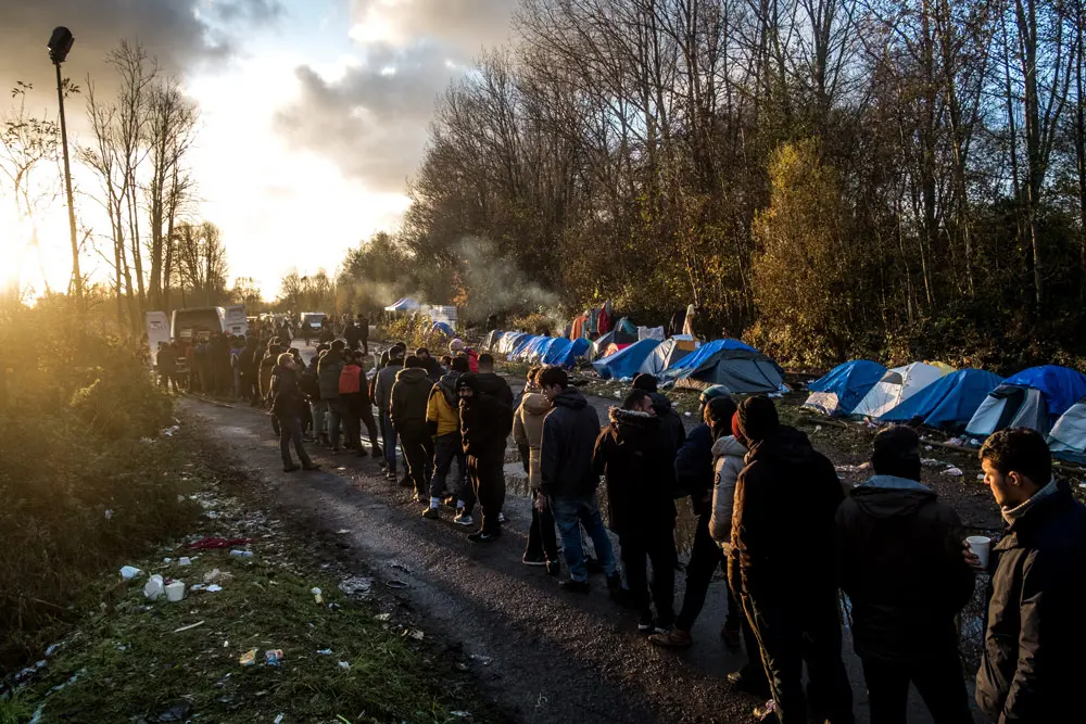 29 November 2021, France, Loon Plage: Refugees wait in lines for the distribution of food by the Refugee community kitchen association. After the evacuation of the Grande Synthe camp on November 16, a new camp composed mainly of Kurdish exiles, has been set up near Grande Synthe. Photo: Michael Bunel/Le Pictorium Agency via ZUMA/dpa.