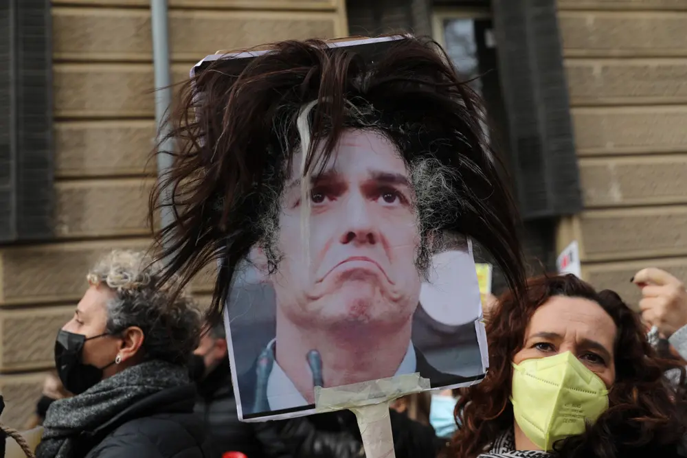 09 December 2021, Spain, Madrid: A demonstrator holds a photo of Spanish Prime Minister Sanchez with hair extensions pasted on it, during a protest by hairdressers and beauticians outside the Senate in Madrid to demand a reduction in VAT. Photo: Isabel Infantes/EUROPA PRESS/dpa.