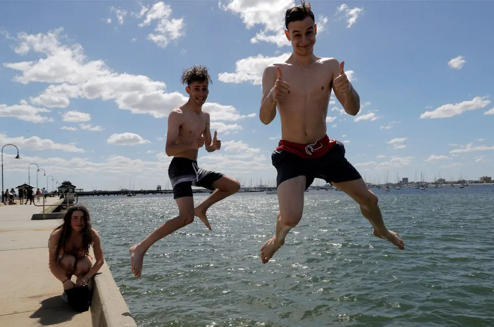 20 December 2021, Australia, Melbourne: People jump off St Kilda Pier into the water at St Kilda Beach in Melbourne. Photo: Con Chronis/AAP/dpa.