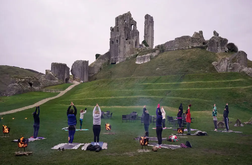 21 December 2021, United Kingdom, Swanage: People take part in a winter solstice yoga session at the National Trust's Corfe Castle in Dorset to mark the solstice and to witness the sunrise after the longest night of the year. Photo: Andrew Matthews/PA Wire/dpa.