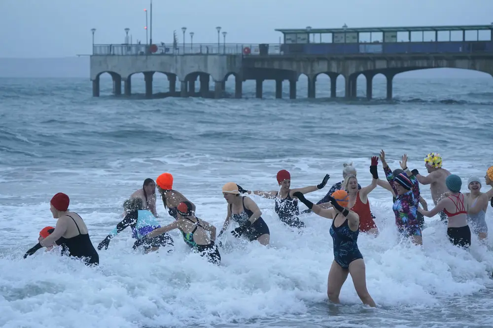01 January 2022, United Kingdom, Bournemouth: A group of people swim in the sea on Boscombe Beach during sunrise. Photo: Andrew Matthews/PA Wire/dpa.