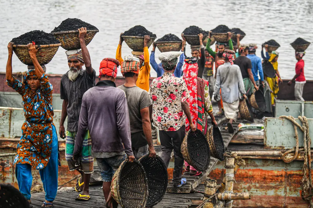 02 January 2022, Bangladesh, Dhaka: Bangladeshi day labourers carry baskets of coal from a cargo ship in Gabtoli. They are earning around $1 every 30 baskets of coal unloaded from the ship. Photo: Piyas Biswas/SOPA Images via ZUMA Press Wire/dpa.