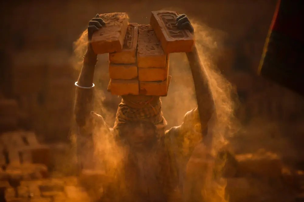 04 January 2022, Nepal, Bhaktapur: A migrant worker balance bricks on his head at a brick kiln. Nepalese and Indian seasonal laborers arrive during the winter season to work at kilns. Photo: Skanda Gautam/ZUMA Press Wire/dpa.