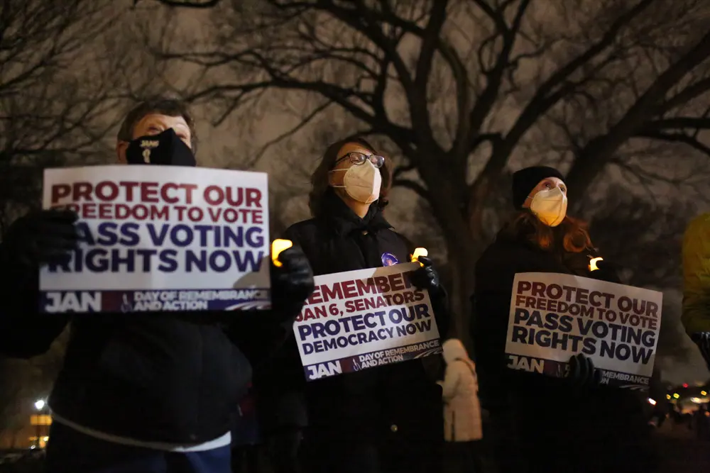 06 January 2022, US, Washington: People hold up candles and placards during a candlelight vigil on the National Mall to mark the first anniversary of the January 6 Capitol riot. A mob of supporters of US President Donald Trump attacked the United States Capitol in Washington on 6 January 2021. Photo: Probal Rashid/ZUMA Press Wire/dpa.