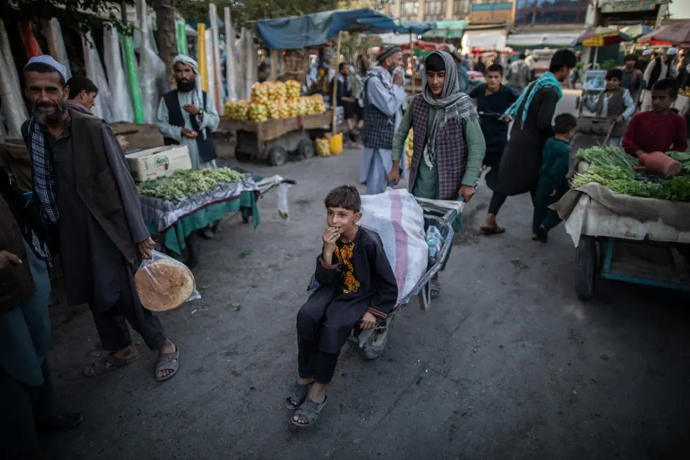 FILED - 17 September 2021, Afghanistan, Kunduz: An Afghani boy rides a wheelbarrow in a market in Kunduz, northern Afghanistan. Afghanistan is facing the largest humanitarian crisis in the world, given the sharp deterioration in its economic conditions since the Taliban seized power last August. Photo: Oliver Weiken/dpa.