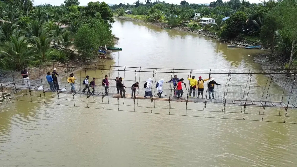 11 January 2022, Malaysia, Sandakan: Several students from Kebangsaan Sibuga Besar school use the dilapidated Nelayan Tengah suspension bridge to attend school sessions. The locals in collaboration with members of the United Malays National Organisation (UMNO) party took the initiative to replace the floor of the suspension bridge which is the communication route for three villages. Photo: Arjasneh Ahmad/BERNAMA/dpa.
