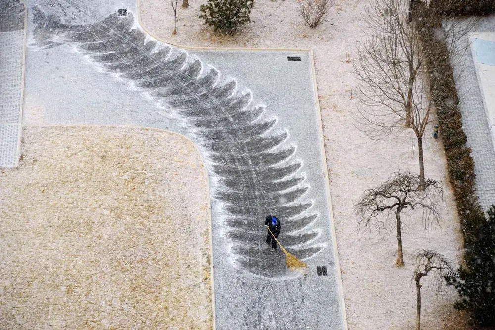 20 January 2022, China, Beijing: A man sweeps snow near Changhua Road in Haidian district, Beijing. Photo: Fan Jiashan/SIPA Asia via ZUMA Press Wire/dpa.