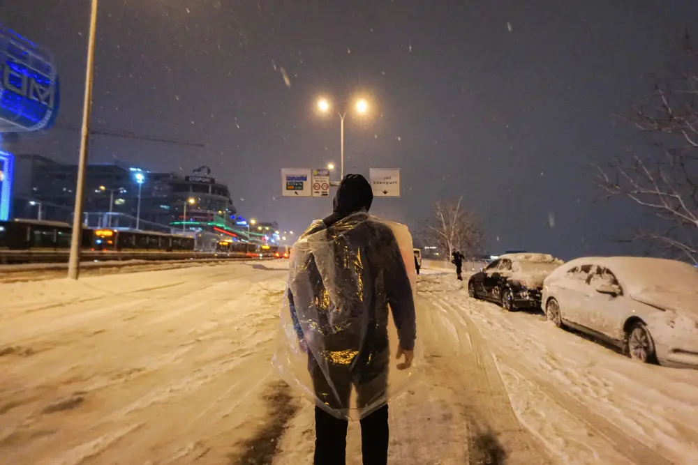 24 January 2022, Turkey, Istanbul: A man walks on a snow-covered highway while protecting his clothes with a plastic wrap during heavy snowfall. Heavy snowfall has caused traffic chaos in Turkey. Photo: Ibrahim Oner/SOPA Images via ZUMA Press Wire/dpa.