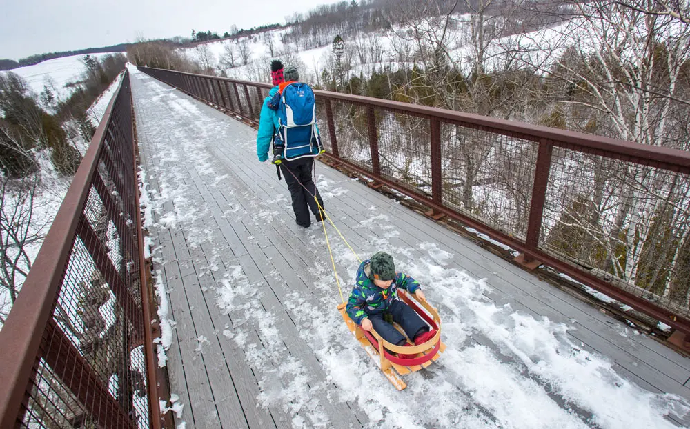 21 February 2022, Canada, Kawartha Lakes: Lindsey Lie-Paehlke with her sons Odin and Lawrence hike across Doube's Trestle Bridge a historical landmark and part of the Trans Canada Trail in Kawartha Lakes. Photo: Fred Thornhill/Canadian Press via ZUMA Press/dpa.
