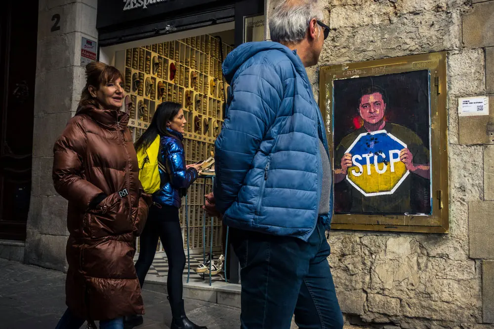 05 March 2022, Spain, Barcelona: Passers-by look at a graffiti by Italian urban artist 'TVBoy', Salvatore Benintende, titled 'Stop The Madness' and depicting Ukrainian president Volodymyr Zelensky holding a Stop sign in the national colors, in protest to the ongoing Russian attacks on Ukraine. Photo: Matthias Oesterle/ZUMA Press Wire/dpa.