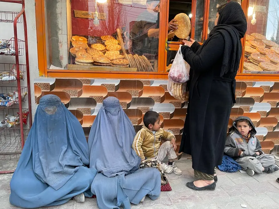 07 March 2022, Afghanistan, Kabul: Poor people sit in front of a bakery waiting for anyone willing to give them a few slices of Afghan flatbread or naan-e-Afghani. Photo: Nina Muslim/BERNAMA/dpa.