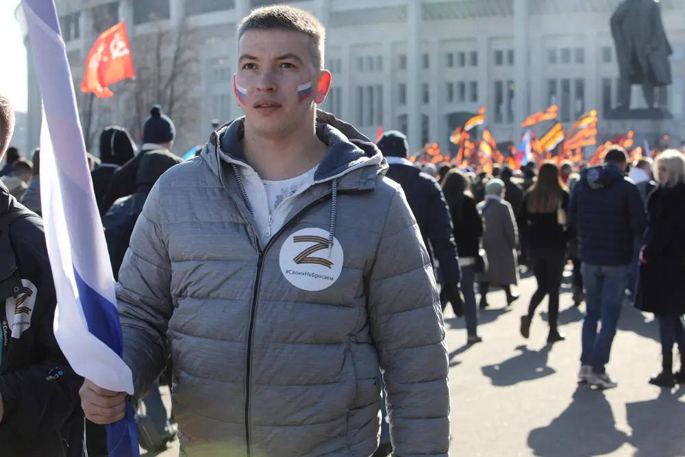18 March 2022, Russia, Moscow: People hold flags on the sidelines of a concert held to mark the eighth anniversary of Russia's annexation of Crimea. Photo: Str/dpa.
