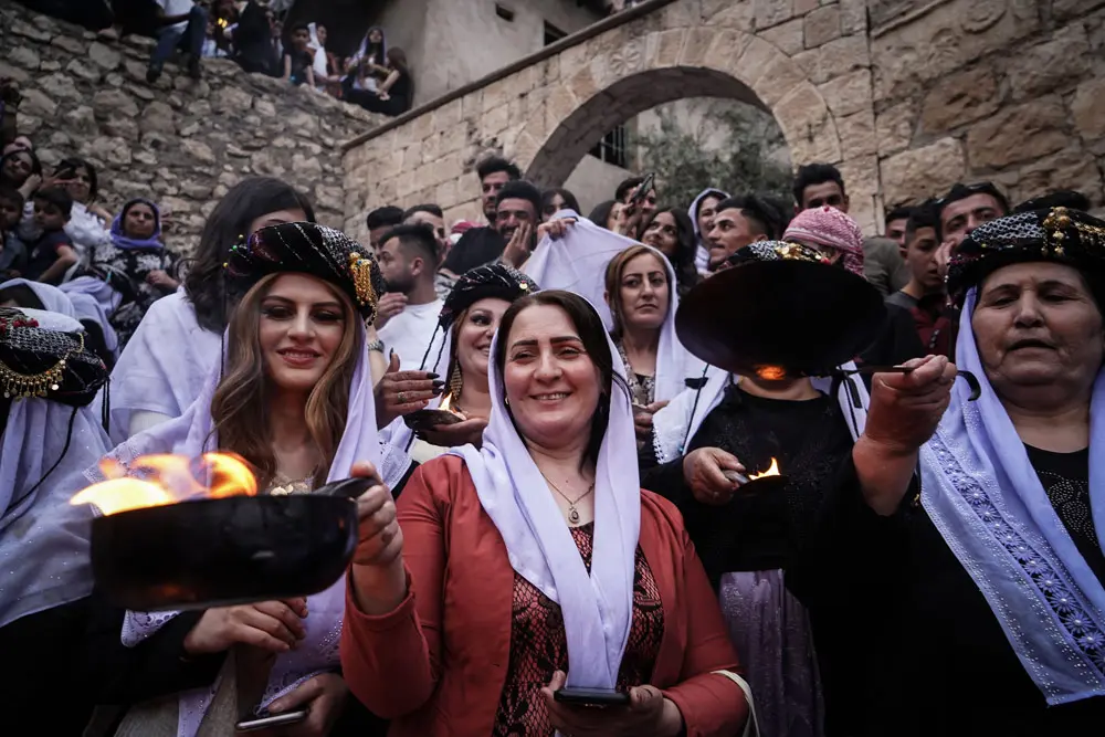 19 April 2022, Iraq, Dohuk: Iraqi Yazidi women hold lit candles and torches at the Lalish mountain valley and temple, the holiest shrine of the Yazidis, during the celebrations of the Red Wednesday, which marks the Yazidi New Year. The Red Wednesday falls on the first Wednesday of April according to the Rumi calendar, and symbolizes the creation of the universe. Photo: Ismael Adnan/dpa.