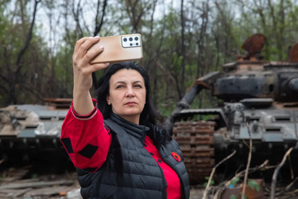 07 May 2022, Ukraine, Kiev: A woman takes a selfie in front of a destroyed Russian tank. Photo: Mykhaylo Palinchak/SOPA Images via ZUMA Press Wire/dpa.