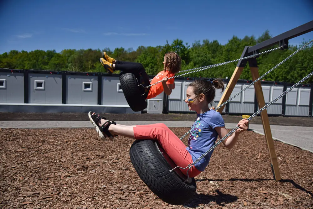 19 May 2022, Ukraine, Lviv: Girls swing at the playground near the modular town for refugees in Lviv. About 300 people live there after fleeing the Russian aggression in Mariupol, Luhansk, Kramatorsk, Kherson and other zones of active hostilities. Photo: Pavlo Palamarchuk/SOPA Images via ZUMA Press Wire/dpa.