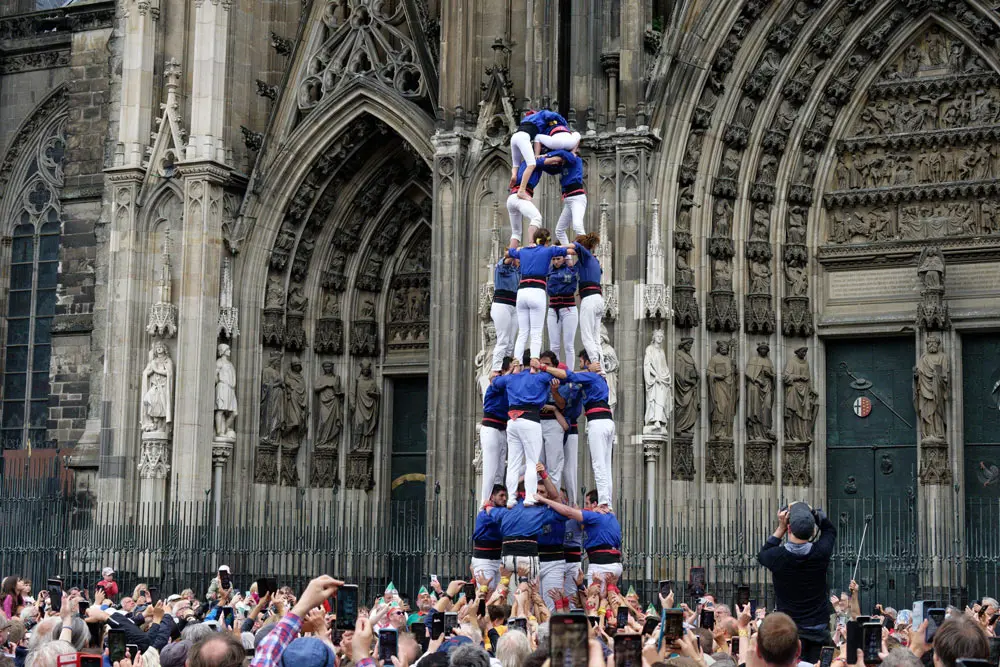 06 June 2022, North Rhine-Westphalia, Cologne: Around 180 members of Barcelona's Castellers de la Vila de Gracia human tower association, build a Catalan human tower in front of Cologne Cathedral. The Castells (human towers) are a UNESCO Cultural Heritage of Humanity. Photo: Henning Kaiser/dpa.
