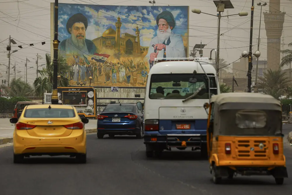 13 June 2022, Iraq, Sadr City: Motorists drive past a poster bearing the images prominent Iraqi Shia clerics. Iraqi lawmakers of the Sadrist bloc, the largest in parliament under leadership of Shia cleric Muqtada al-Sadr, have resigned amid an ongoing political stalemate over forming a new government. Photo: Ameer Al-Mohammedawi/dpa.