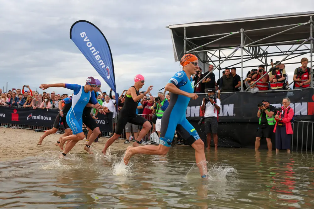 26 June 2022, Hessen, Frankfurt_Main: Athletes run into the Long Forest Lake at the start of the Women's Ironman European Championship. Photo: Joaquim Ferreira/dpa.