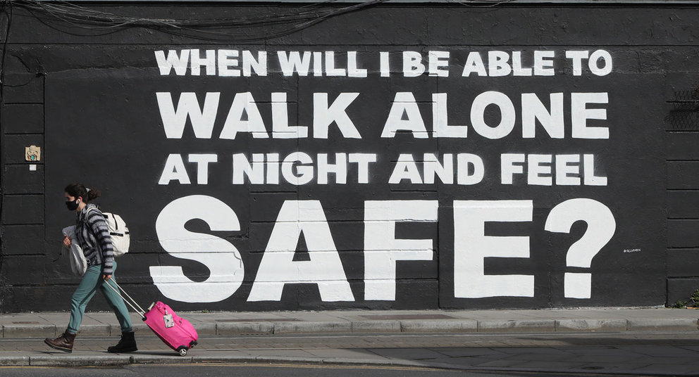 29 March 2021, Ireland, Dublin: A woman walks past the latest mural by Irish artist Emmalene Blake in Dublin city center, which is related to violence against women in the wake of the death of Sarah Everard. Photo: Niall Carson/PA Wire/dpa