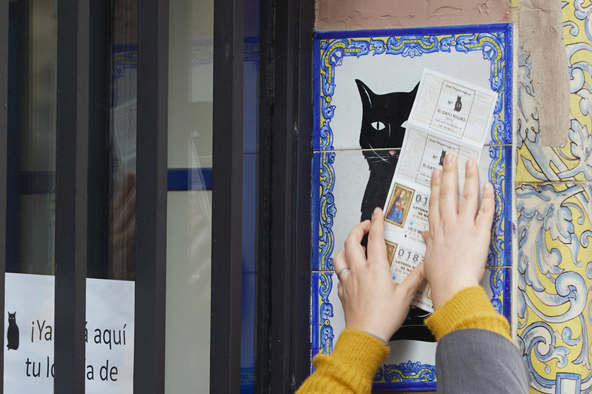 10 December 2021, Spain, Sevilla: A person rubs a Christmas Lottery ticket by the tile of the Lottery Administration El Gato Negro in Seville, a day before Spain's extraordinary Christmas lottery draw. Photo: Joaquin Corchero/EUROPA PRESS/dpa.