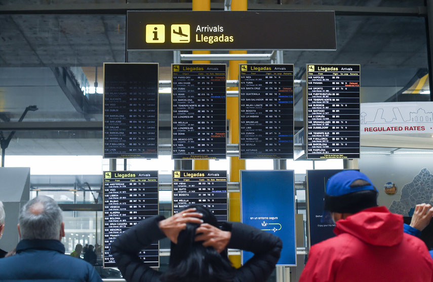 23 December 2021, Spain, Madrid: People look at the arrivals schedule on a display board at Adolfo Suarez airport on the day before Christmas Eve. Photo: Gustavo Valiente/EUROPA PRESS/dpa.