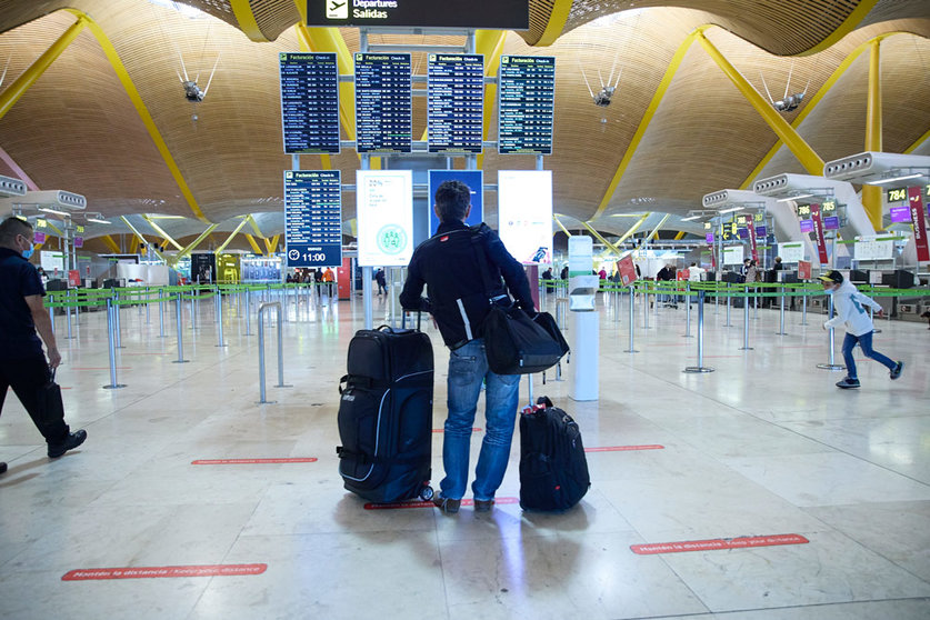 05 January 2022, Spain, Madrid: A traveller stands with his luggage as he looks at the display board at Adolfo Suarez Airport in Madrid. Photo: Jesús Hellín/EUROPA PRESS/dpa.