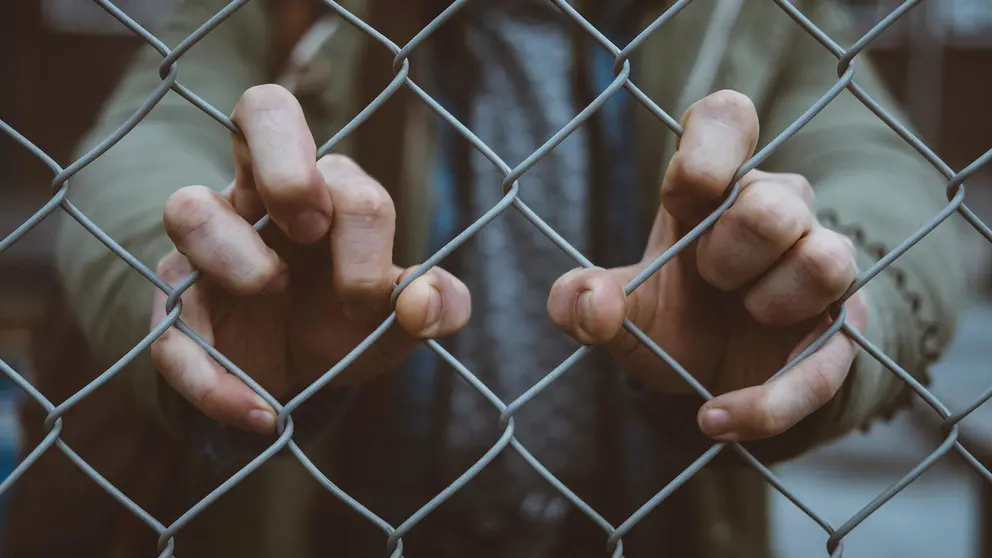 Refugees fence hands Photo by Mitch Lensink