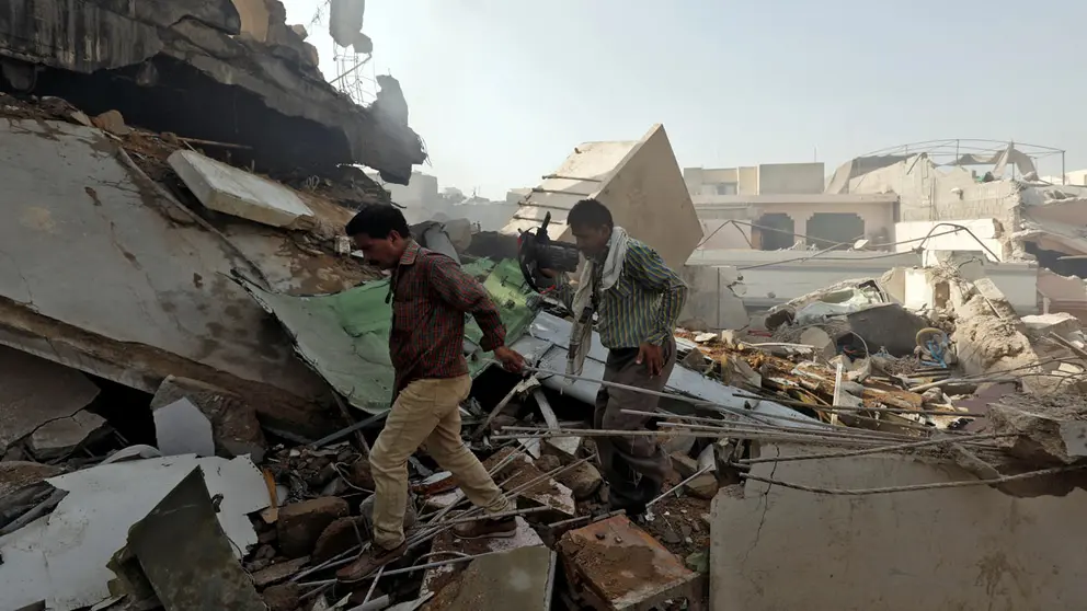 Men walk on the debris at the site of a passenger plane crash in a residential area near an airport in Karachi, Pakistan May 22, 2020. REUTERS/Akhtar Soomro