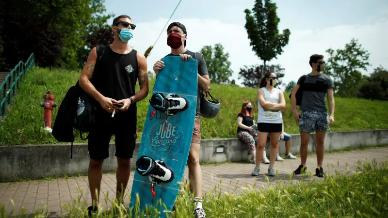 FILE PHOTO: A man wearing a face mask holds a wakeboard at Idroscalo artificial lake, as Italy eases some of the lockdown measures put in place during the coronavirus disease (COVID-19) outbreak, in Milan, Italy, May 23, 2020. REUTERS/Alessandro Garofalo