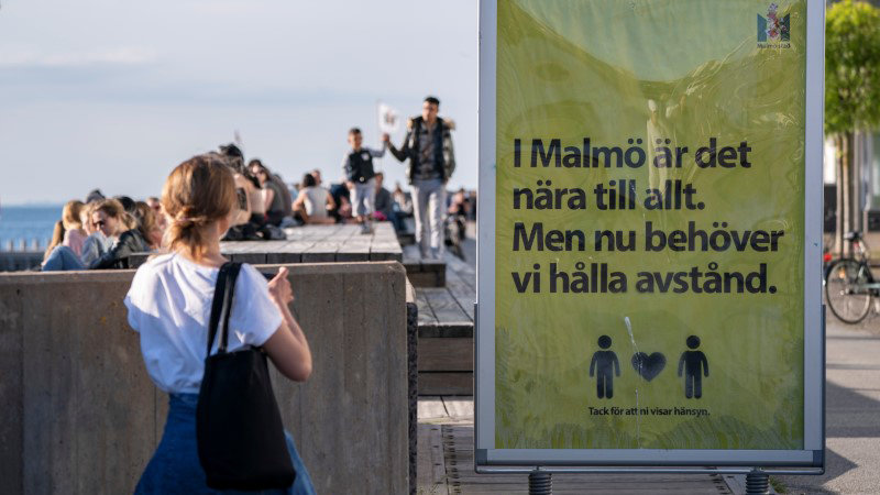 FILE PHOTO: People enjoy the warm evening at Sundspromenaden as the sign reads &#34;In Malmo everything is near. But now we need to keep a distance&#34; in Malmo, Sweden May 26, 2020. TT News Agency/Johan Nilsson via REUTERS