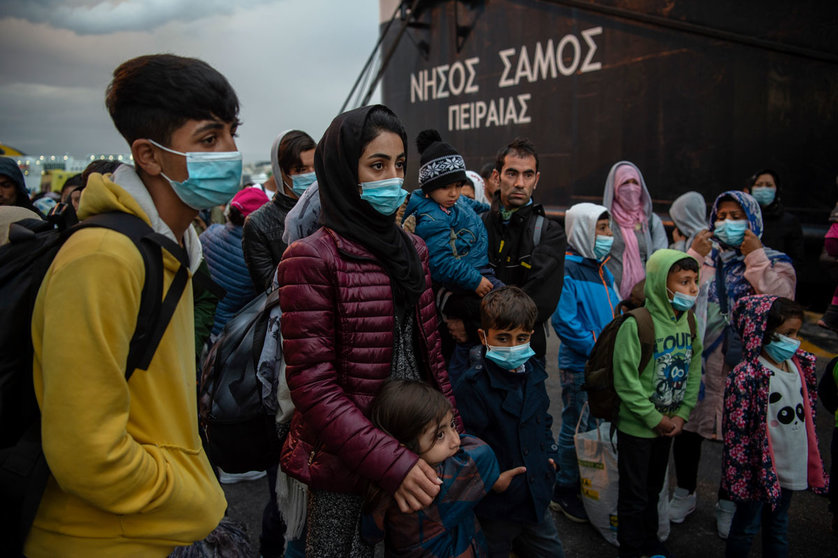 Migrants with face masks from the Moria camp, who arrived by ship from the island of Lesbos, stand in the port of Piraeus near Athens after their arrival. Greek authorities transferred some 400 migrants, mostly families, to the mainland to ease the situation in the overcrowded Moria refugee camp on the island of Lesbos. Photo: Angelos Tzortzinis/dpa/dpa
