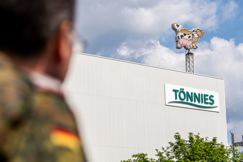 A soldier of the German Armed Forces looks at the logo of the Toennies meat factory, which had to halt operations after hundreds of employees at the family owned business had contracted coronavirus. Photo: David Inderlied/dpa