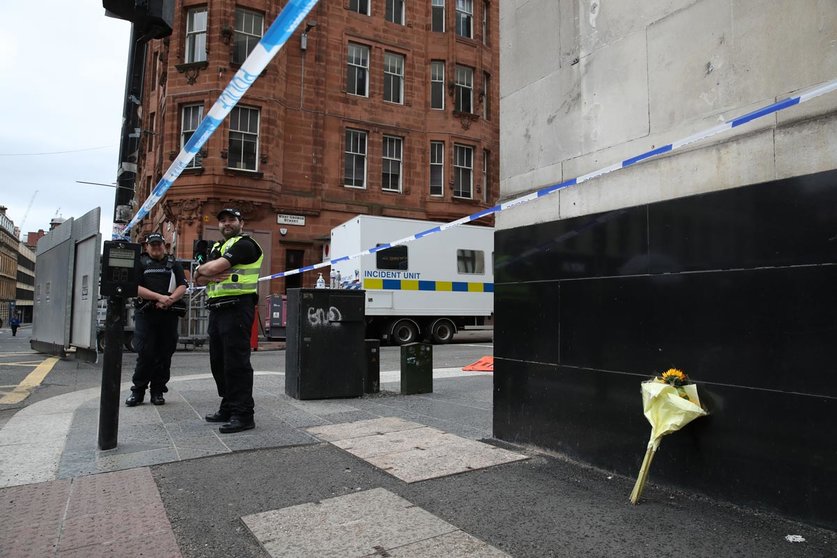 Police officers stand near a floral tribute at the crime scene on West George Street, where a man was shot Yesterday by an armed officers after another police officer was injured during an attack on Friday. Photo: Andrew Milligan/PA Wire/dpa