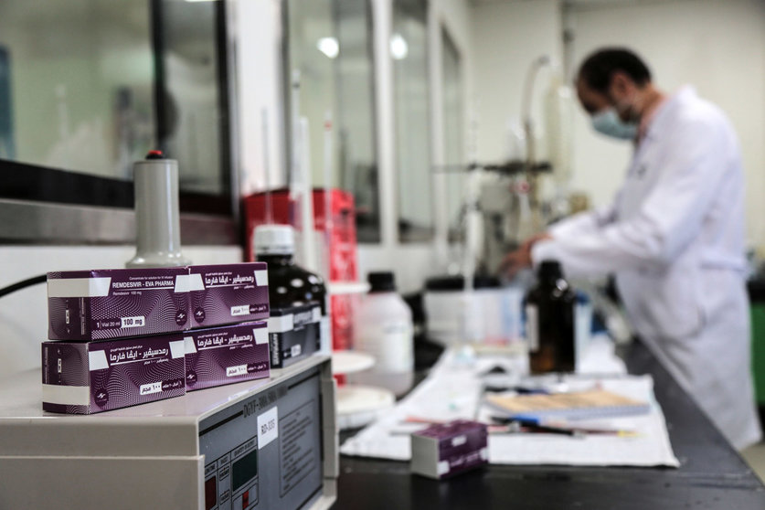 Packs containing vials of Remdesivir, a broad-spectrum antiviral medication approved as a specific treatment for COVID-19, lie next to an employee of Egyptian pharmaceutical company Eva Pharma at the company&#39;s factory, which started producing the drug this week with a production capacity of up to 1.5 million doses per month. The European Commission says it has approved the use of the medication remdesivir to treat severe cases of Covid-19 in the European Union. Photo: Fadel Dawood/dpa