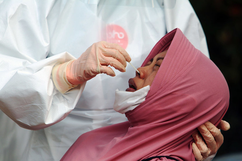 Indonesia, Surabaya: A medical worker takes a swab from a woman at a test station for coronavirus (Covid-19). Photo: Budiono/Sijori Images via ZUMA Wire/dpa