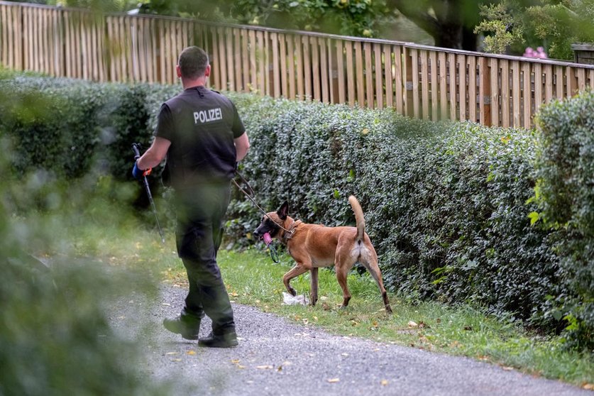 28 July 2020, Lower Saxony, Seelze: A police officer with a dog searches an area inside a garden as part of an investigation plan to find any clues about the disappearance of the British girl Madeleine McCann on 3 May 2007. Photo: Peter Steffen/dpa.