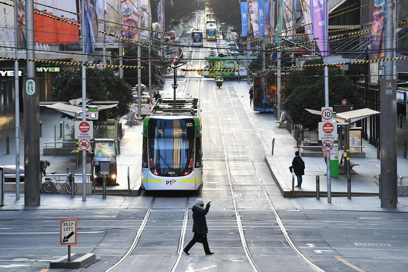 04 August 2020, Australia, Melbourne: A woman wearing a face mask walks across Bourke Street Mall in Melbourne, after the second night under curfew amid the spread of the coronavirus (COVID-19). Photo: James Ross/AAP/dpa