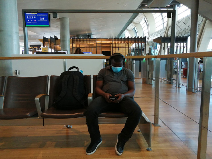 A man wearing a face mask waits at Oslo airport to board a flight to Helsinki. Photo: Foreigner.fi.