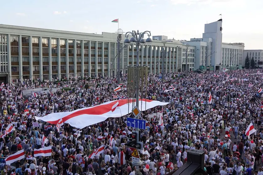 16 August 2020, Belarus, Minsk: People carry the historical Belarusian flag during a protest against Belarusian President Alexander Lukashenko at Independence Square. Photo: Ulf Mauder/dpa