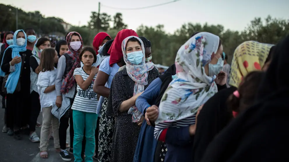 10 September 2020, Greece, Moria: Migrants queue to get food, near the burnt-out Moria refugee camp that was almost completely destroyed in a fire the broke out overnight on Wednesday. More than 12,000 migrants, who lost what homes they had in the blaze that might have been intentionally set, had to spend the night on the streets. Photo: Socrates Baltagiannis/dpa