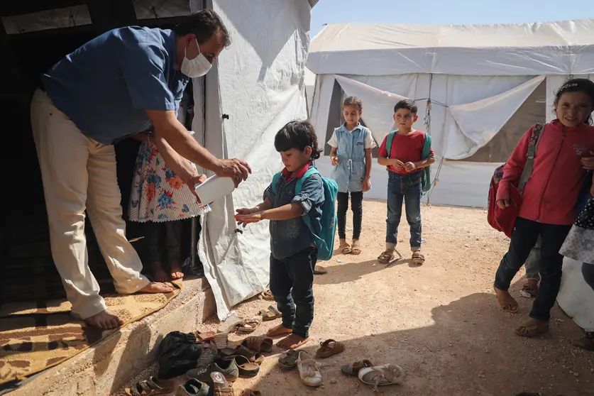 27 September 2020, Syria, Idlib: A teacher disinfects a child hands at a school in the town of Batenta camp in Idlib governorate on the first day of the school year, amid the spread of the coronavirus. Photo: Anas Alkharboutli/dpa.