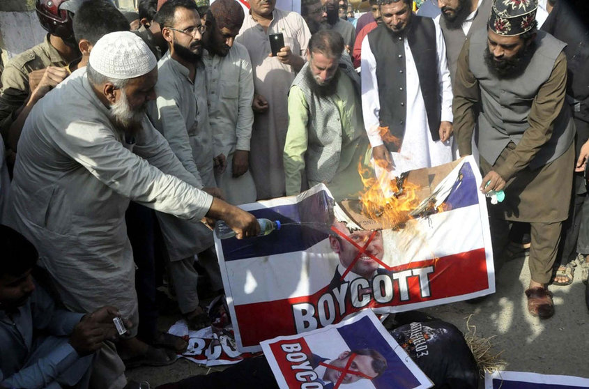 27 October 2020, Pakistan, Karachi: Pakistani demonstrators burn a banner depicting French President Emmanuel Macron on the French flag, during a protest against Macron&#39;s comments on Islam&#39;s prophet Muhammad cartoons. Photo: Ppi/dpa.