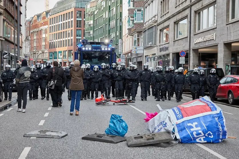 22 November 2020, Hamburg: Police officers run in the form of a police chain in front of a water cannon as protesters set up their barricades during a protest against the measures of the German government amid the coronavirus pandemic. Photo: Georg Wendt/dpa