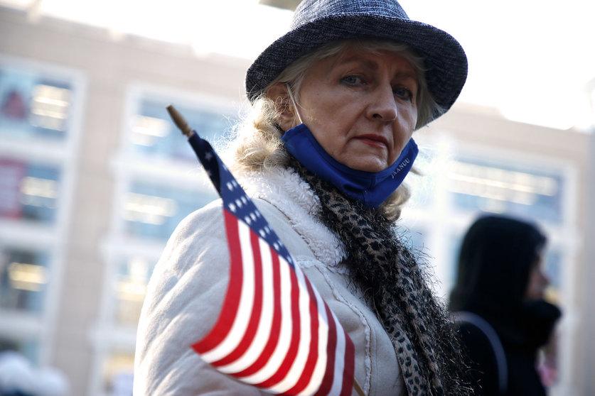 29 November 2020, US, New York: A protester holds an American Flag during a rally in Union Square Park against coronavirus lockdown. Photo: John Lamparski/SOPA Images via ZUMA Wire/dpa