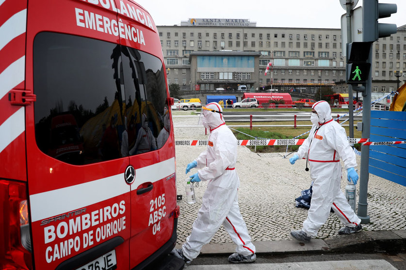 29 January 2021, Portugal, Lisbon: Health care workers in protective suits walk past an ambulance at the new triage center for coronavirus patients at Santa Maria Hospital. Photo: Pedro Fiuza/ZUMA Wire/dpa