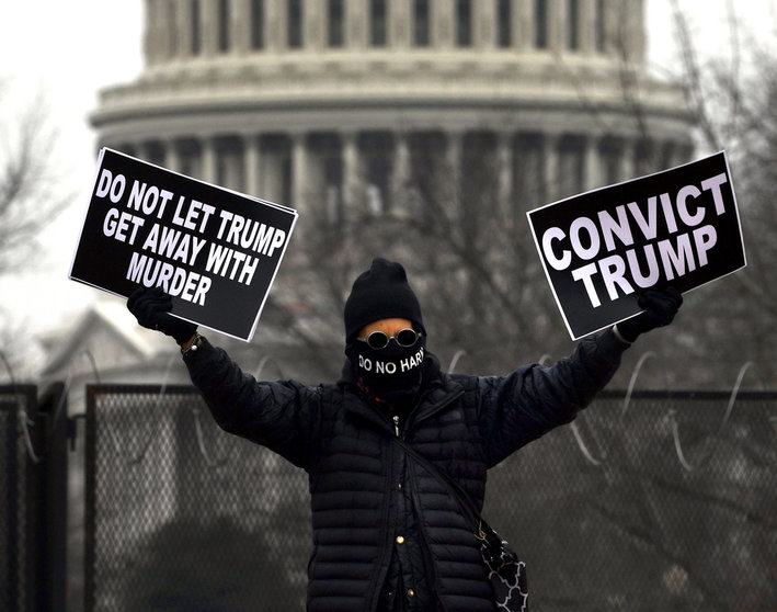 13 February 2021, US, Washington: A protester hold signs near Union Station during the fifth day of the second impeachment trial of US President Trump in the Senate. Photo: Carol Guzy/ZUMA Wire/dpa