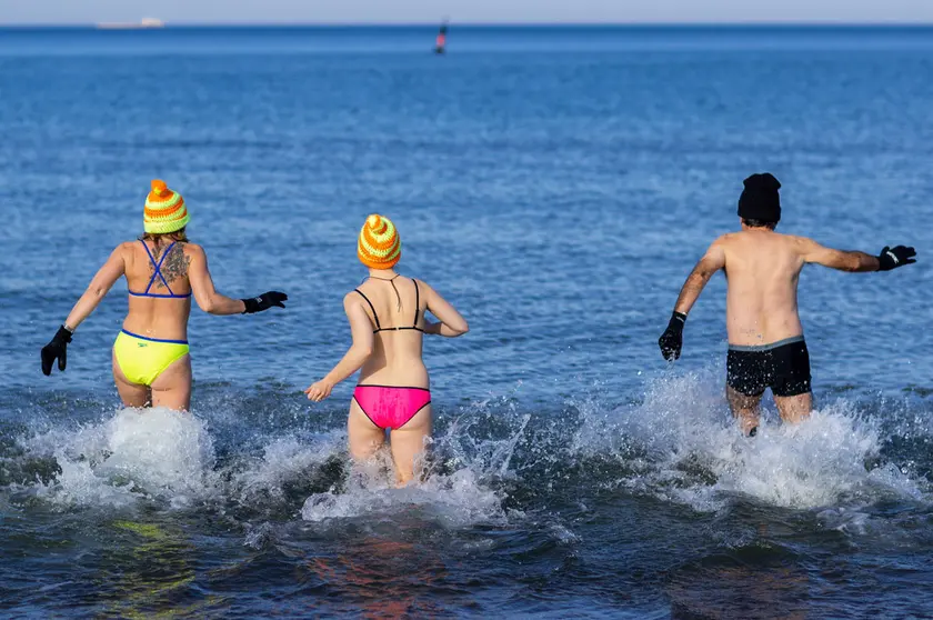 21 February 2021, Mecklenburg-Western Pomerania, Warnemuende: Members of the ice-bathing club "Rostocker Seehunde" run for a swim in the Baltic Sea on the beach of Warnemuende. Photo: Jens Büttner/dpa-Zentralbild/dpa